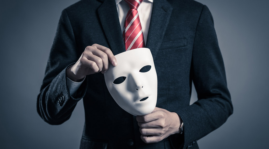 Man wearing a suit holding a white mask with his both hands 