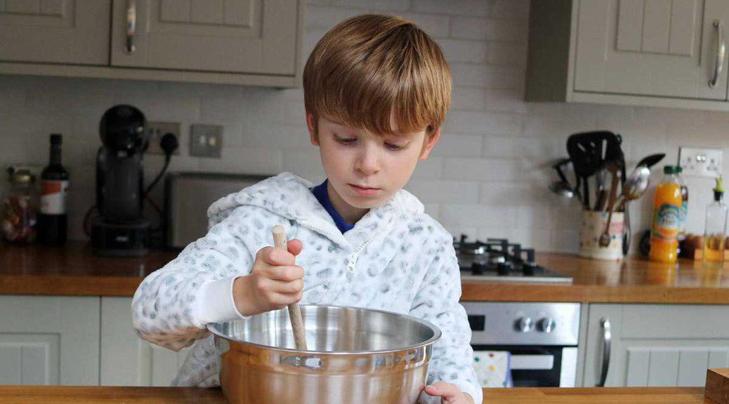 Little boy trying to cook at kitchen