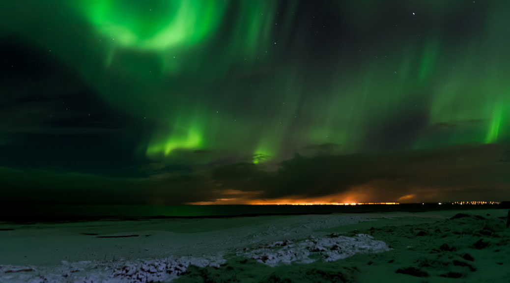 Northern Lights, polar lights above the hills at Reykjavik in winter