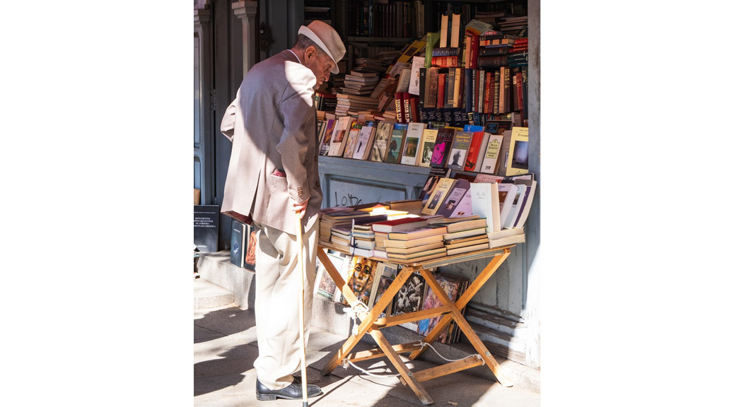 An Old man looking at books shops at a street