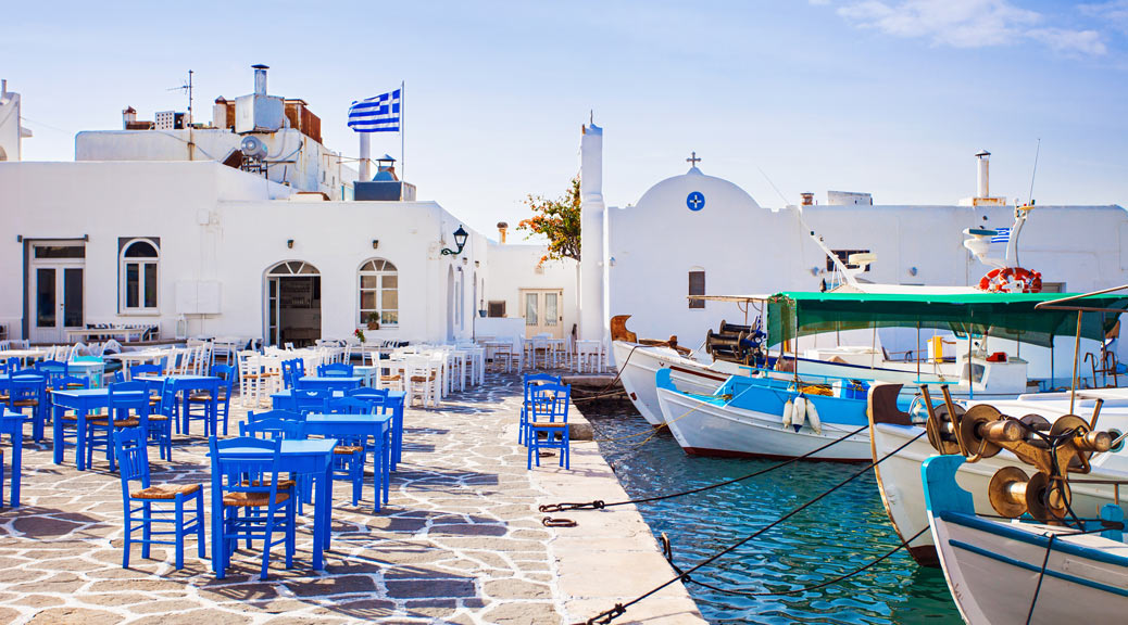 Greek fishing village in Greece with restaurant chairs 