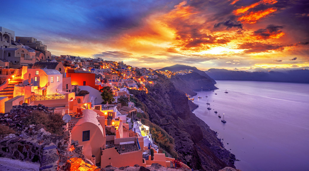 Old Town of Oia or Ia on the island Santorini, white houses, windmills and church with blue domes at sunset, Greece