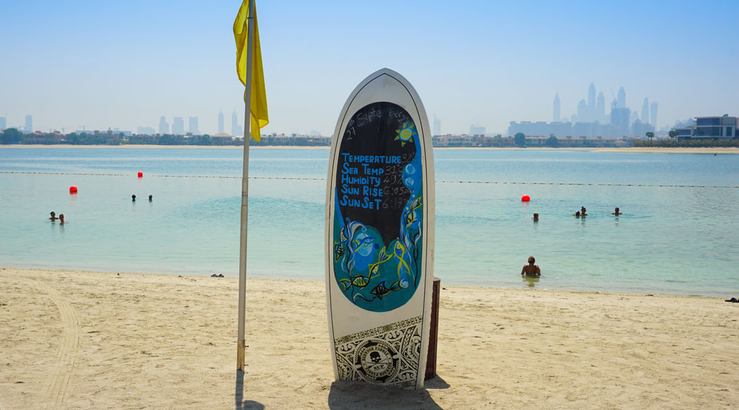 surf board standing with a yellow flag at the beach of Sofitel the palm resort and spa dubai uae