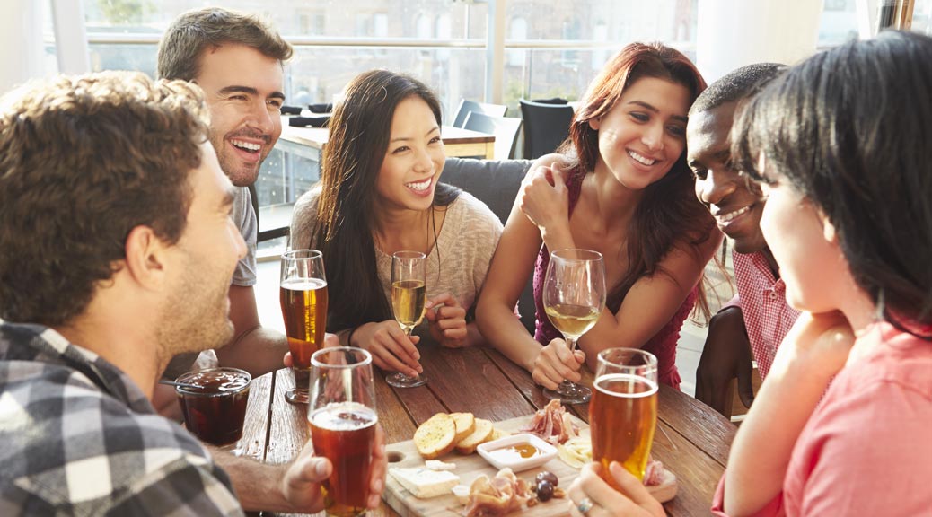 Group Of Friends Enjoying Drink And Snack In Rooftop Bar