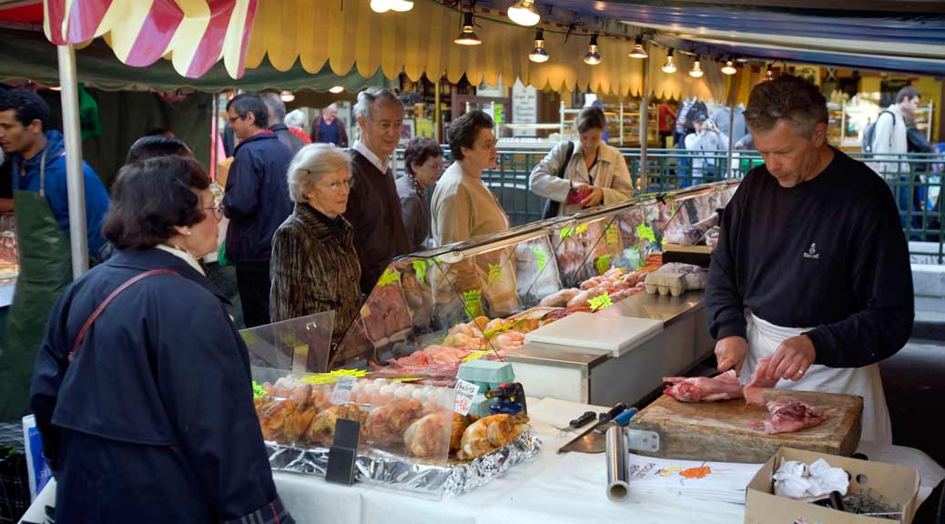 butcher cutting meat at saint germain outdoor market in paris