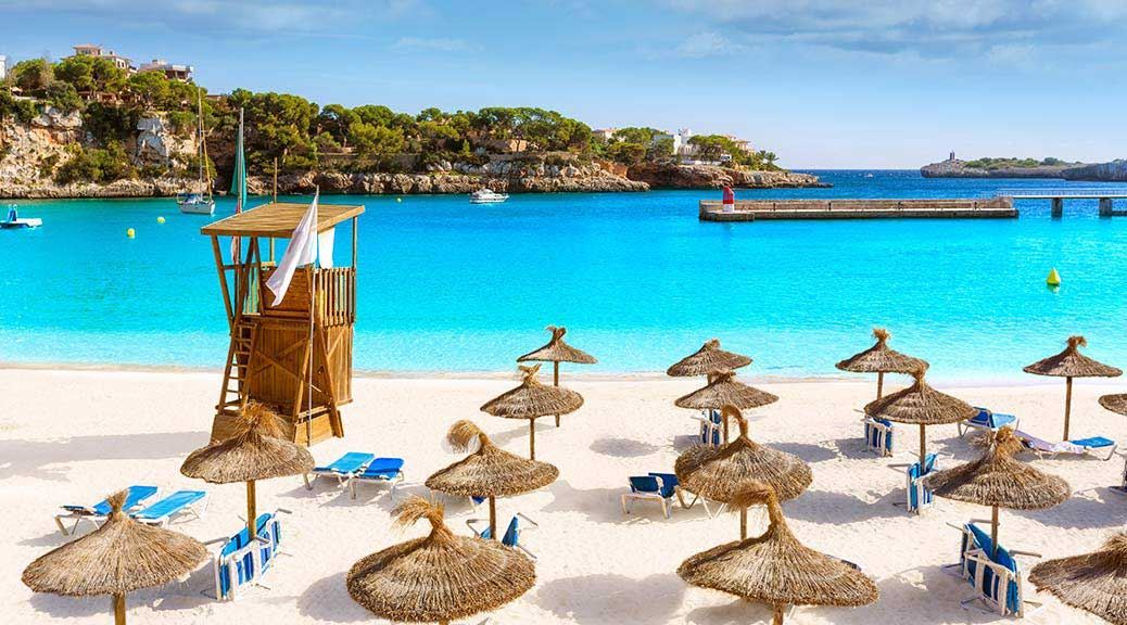Sunbeds and umbrella with lifeguard cabin on white sand beach of majorca 