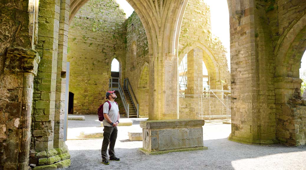 Male tourist in Jerpoint Abbey, a ruined Cistercian abbey, founded in the second half of the 12th century, located near Thomastown, County Kilkenny, Ireland.
