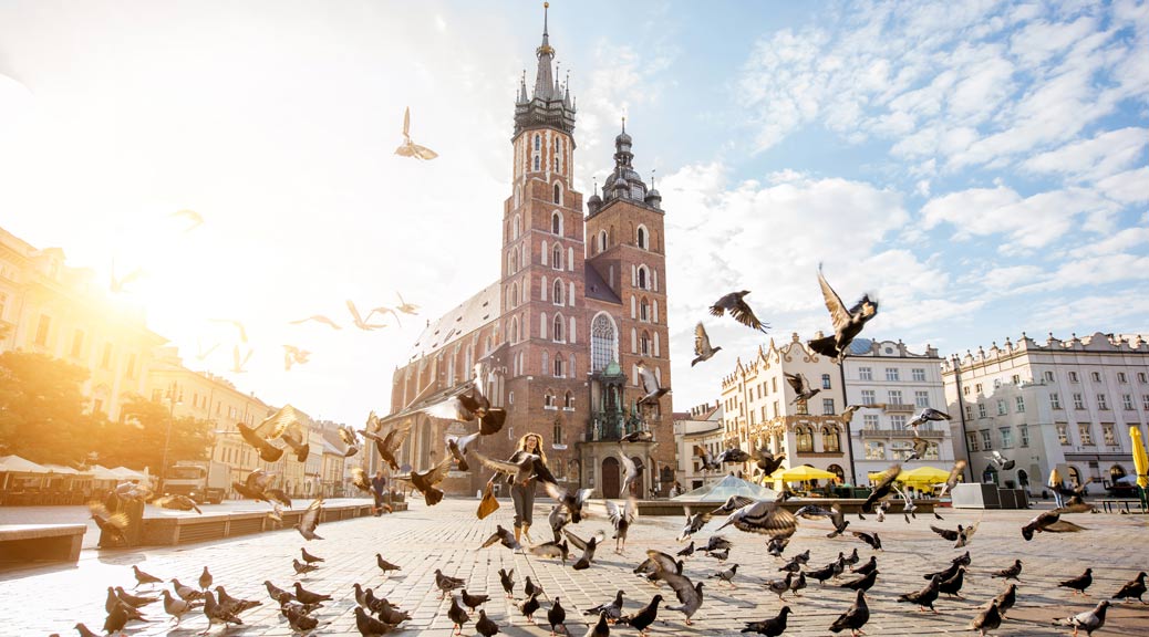 View on the central square and famous st. Marys basilica with pigeons flying during the sunrise in Krakow, Poland By rh2010