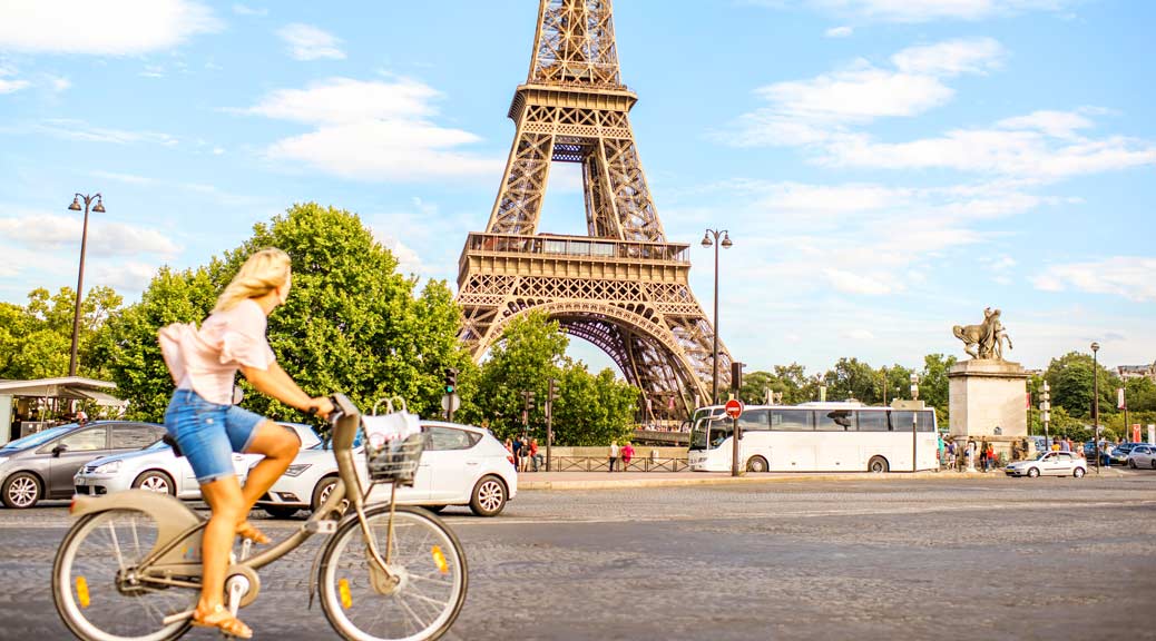 active young woman going by bike near eiffel tower in paris