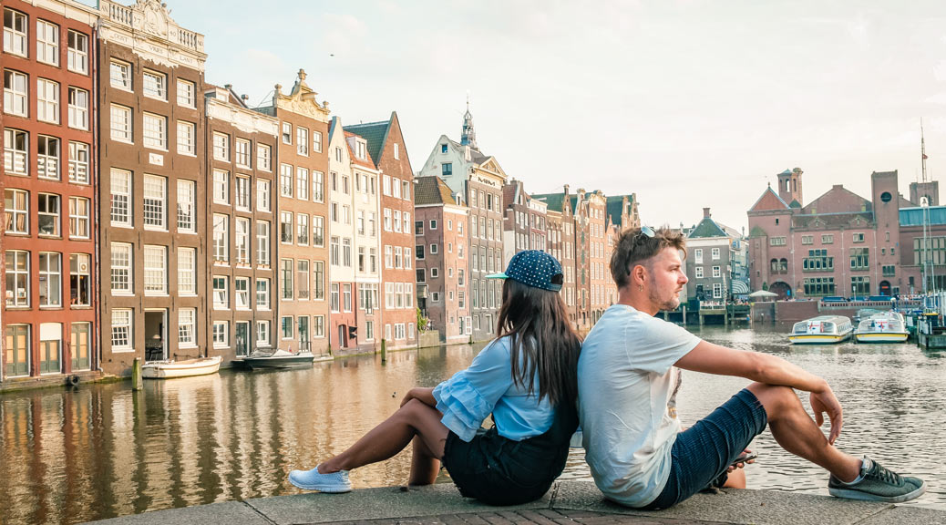 happy couple man and woman on a summer evening at the canals during sunset Amsterdam Damrak