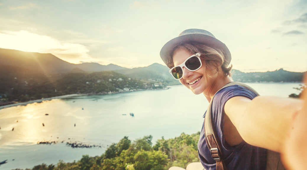 young woman traveler in sunglasses makes selfie with sea view