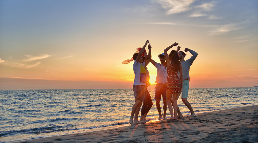 happy young people dancing at the beach on beautiful summer sunset