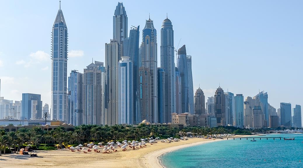 Beautiful sandy beach with palm grove on Dubai Marina skyline