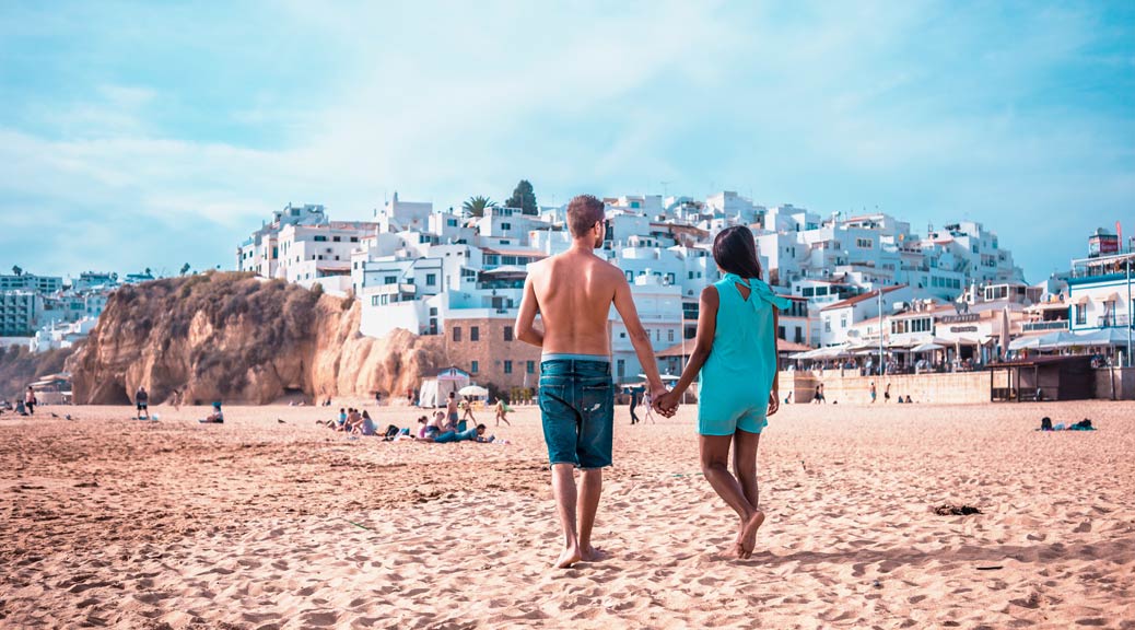 Happy young couple walking on the beach of Albufeira Algarve Portugal
