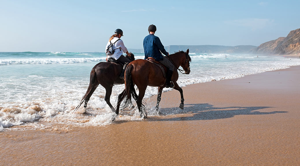 couple riding horses on the beach of sardinia