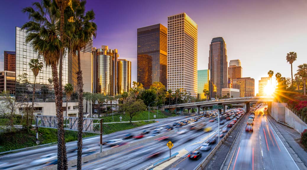 Los Angeles downtown skyline against busy highway during sunset