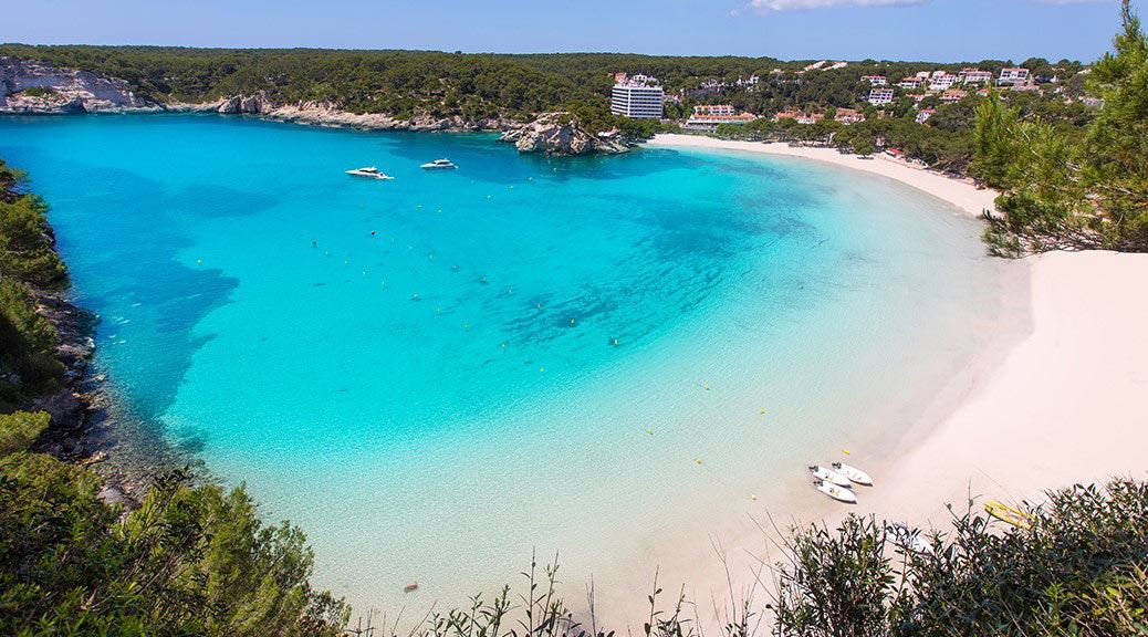 View of sail boats sailing in the beautiful bay with clear turquoise water near beach of Cala Galdana, Menorca island