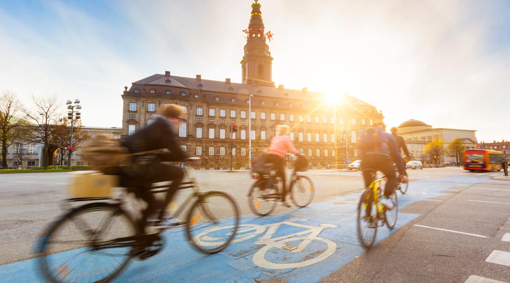 people going by bikes in copenhagen in front of christiansborg palace
