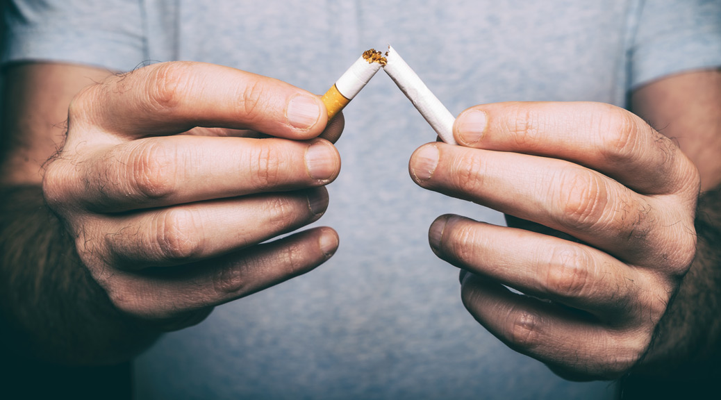 close up of two male hands breaking a cigarette in two