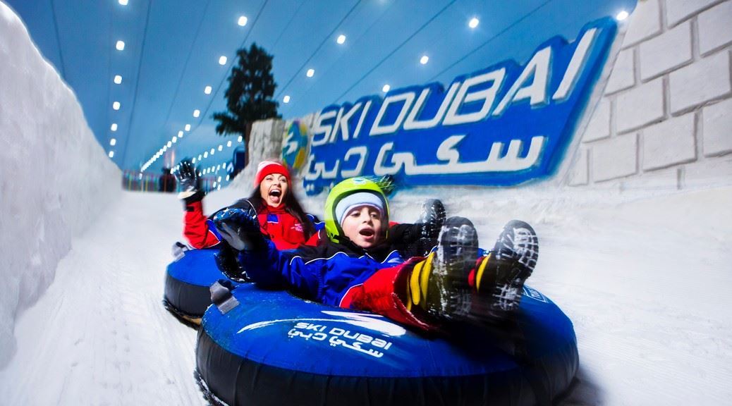 mother and son sliding on the artifical snow on an inflatable tube in Ski Dubai