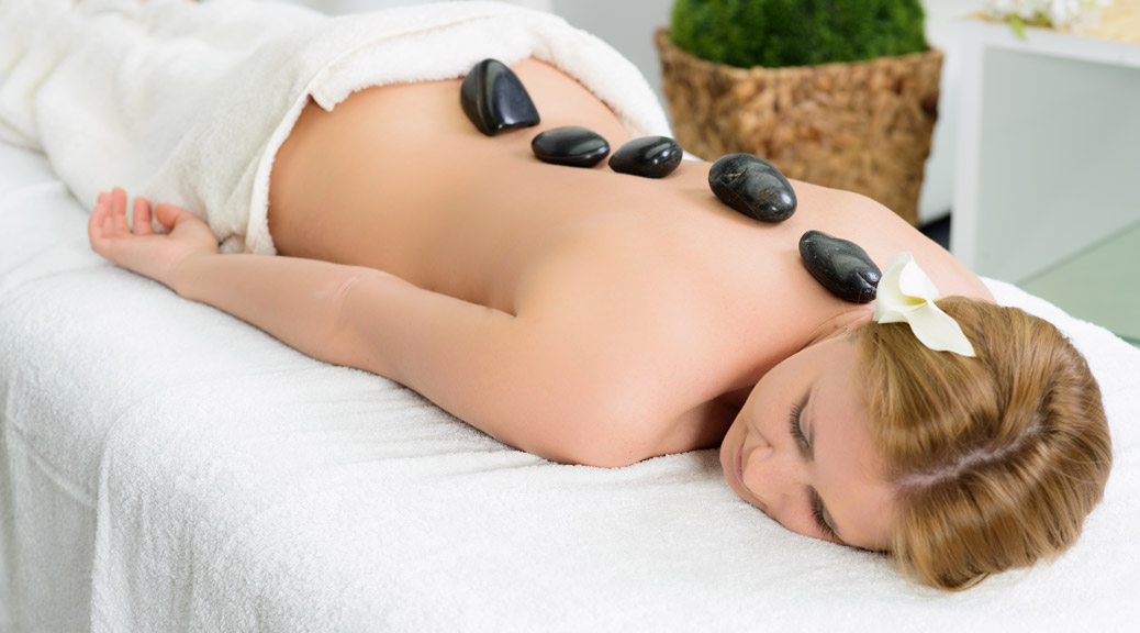 Beautiful young woman getting spa massage, lying on salon